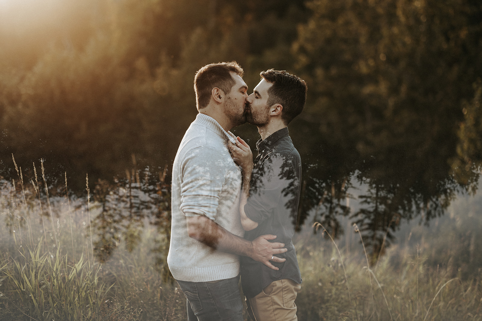 A gay couple kissing in the forest at sunset.