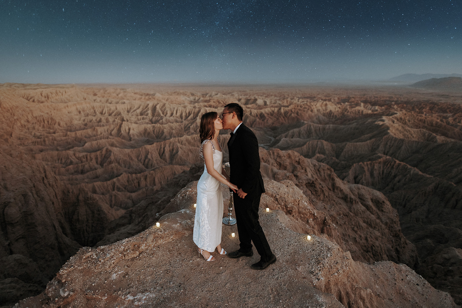 A wedding couple kissing at night overlooking a desert canyon near Palm Springs.