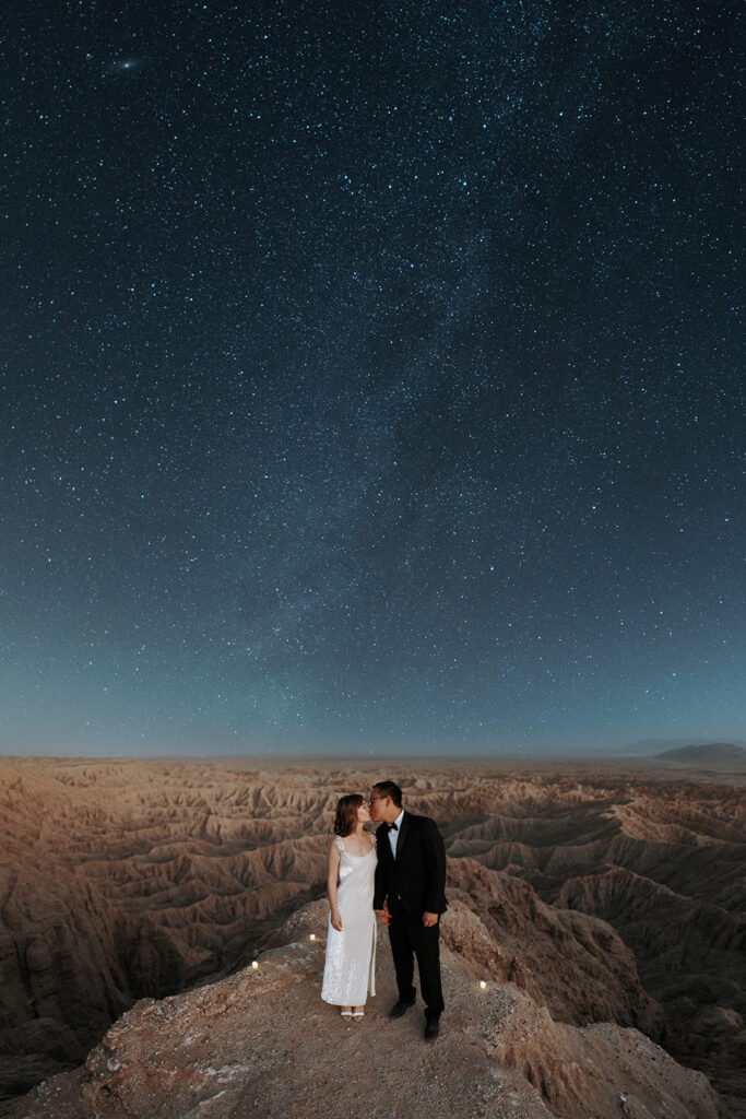 A wedding couple kissing under the milky way.