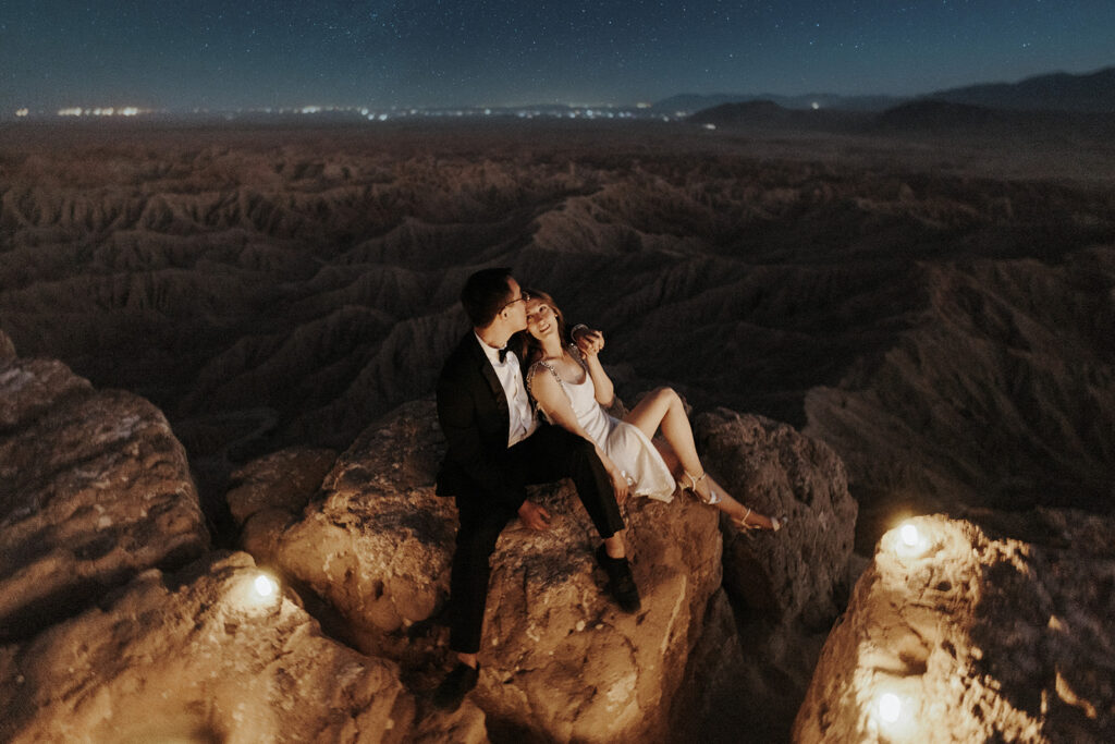 A couple sitting next to each other in the desert under the stars.