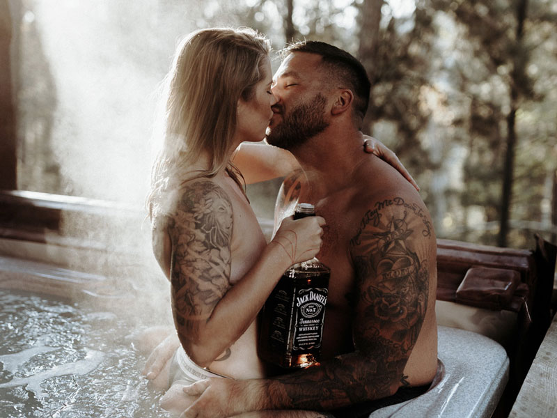 A couple in swimming suits kissing in a hot tub during their boudoir photos.