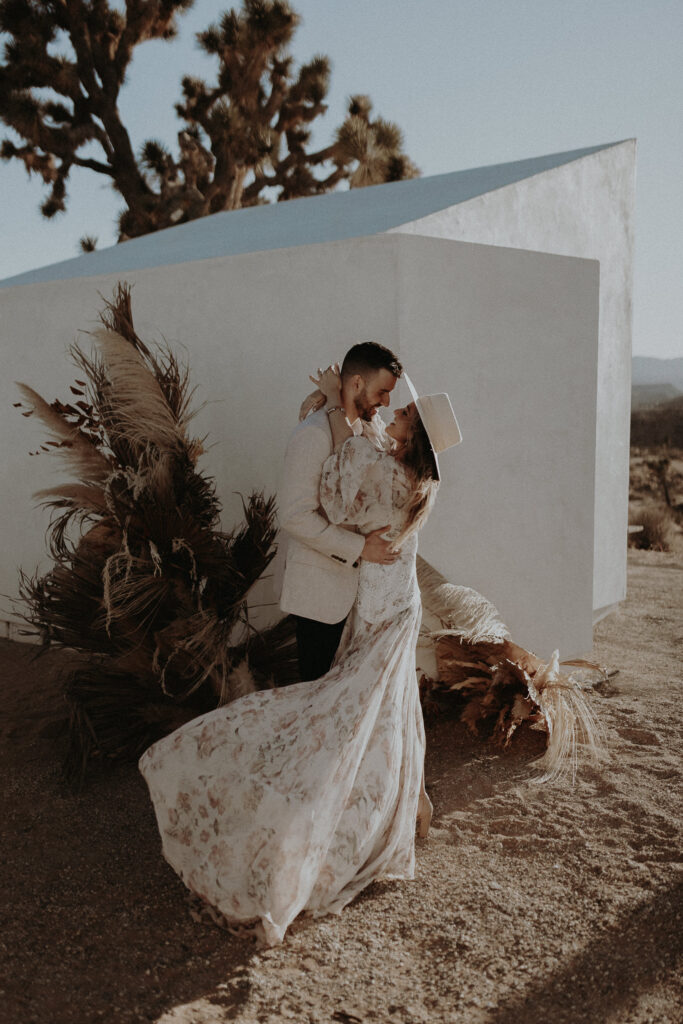 A boho bride and groom wearing light colors kissing at Le Chacuel, a Joshua Tree airbnb.
