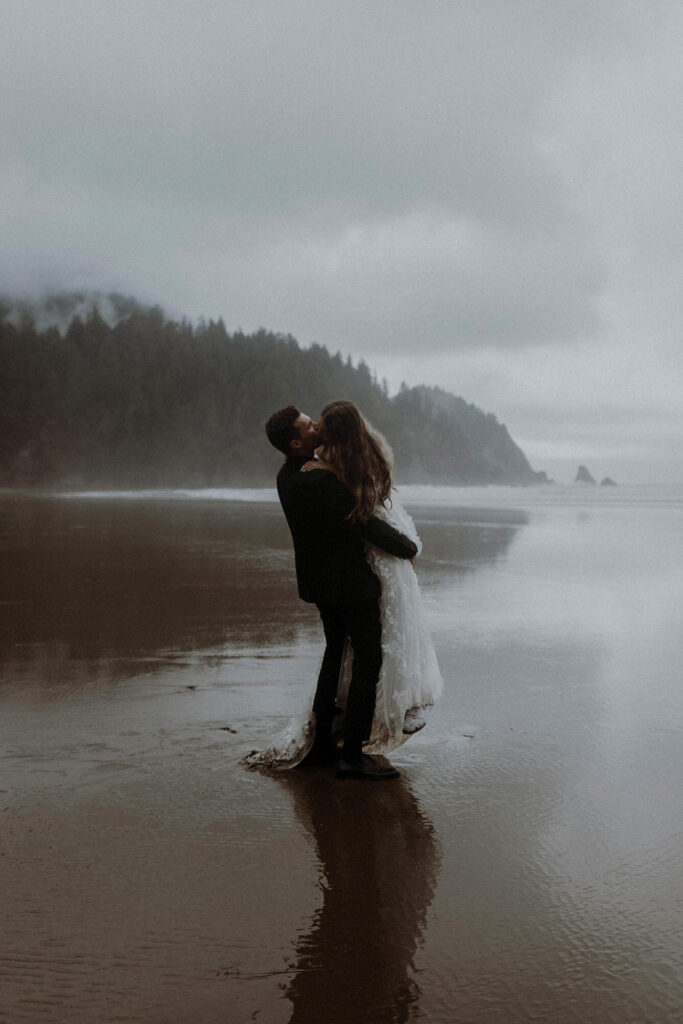 A wedding couple kissing at Short Sand Beach on a foggy morning in Ecola State Park, Oregon.