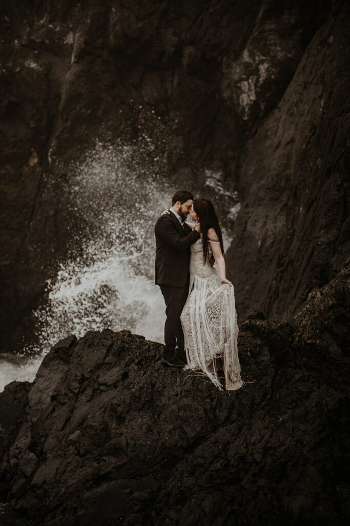 An elopement couple embracing near a wave on the rocks at Sisters Rock State Park in Southern Oregon.